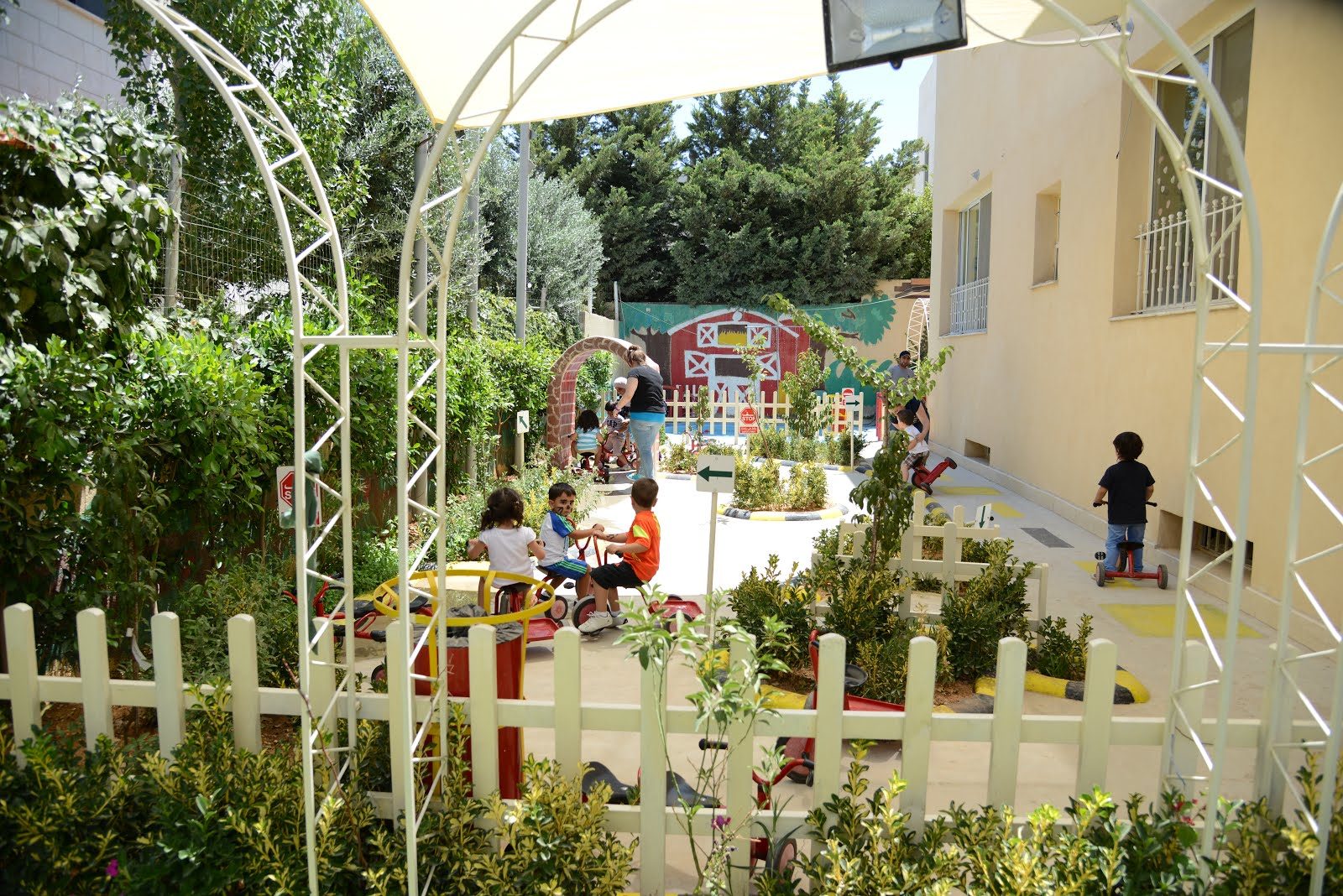 Children riding tricycles in the garden traffic-land at Lubna's Pre School
